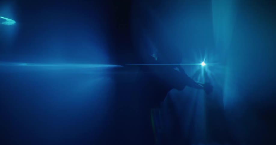In a dark room there are shiny blue disco light with a person dancing in the dark