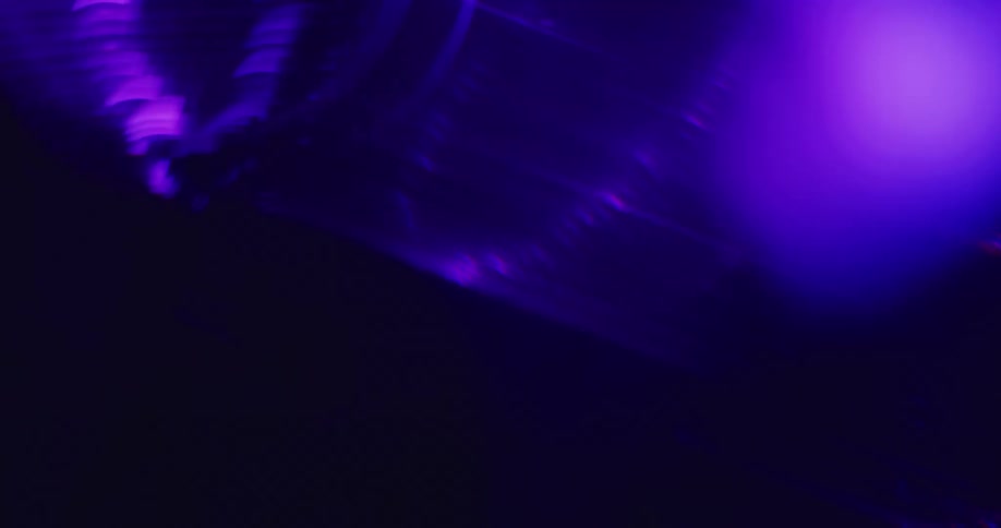 Several beams of rotating blue light being shot forward against a black background