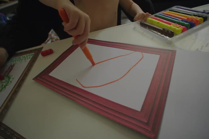 A child drawing with colorful crayons on paper