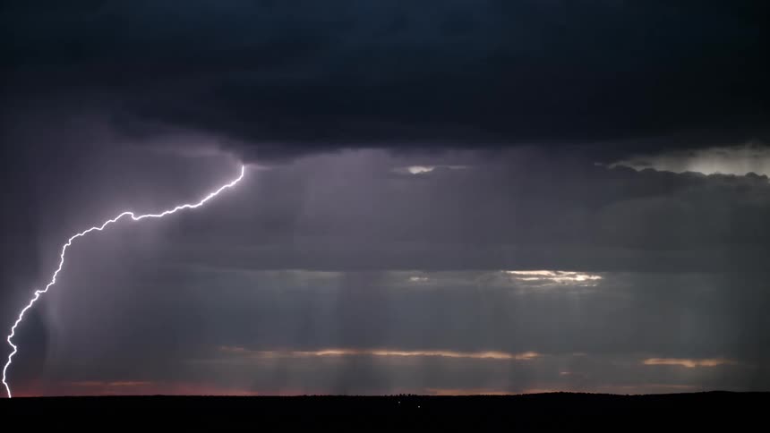 A thunderstorm in the horizon of a landscape at dusk