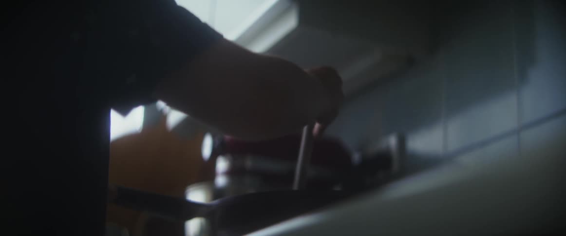 Close up of a person stirring with a spoon on a stove in their kitchen