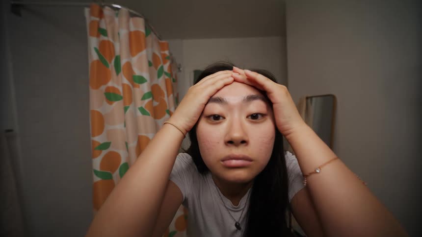 A young woman checking her face for blemishes on the skin