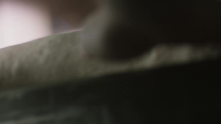 A baker is rolling a dough on the table to make a bread