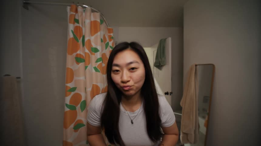 A young woman smiling making faces and fiddling with her hair in the bathroom