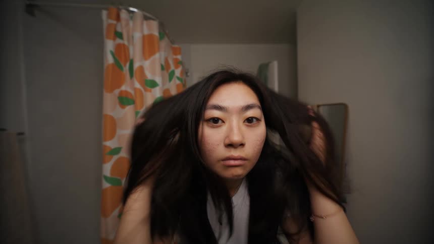 A young woman adjusting her hair until she smiles satisfied