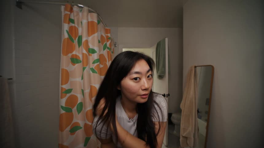 A young woman smiling making faces and adjusting her hair as she takes selfies with her smart phone