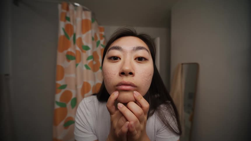 A young woman checking several parts of her faces skin for blemishes