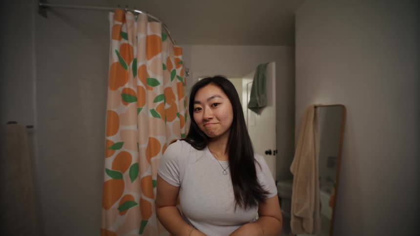A close up of a woman fixing her hair in a bathroom mirror before walking out of the bathroom