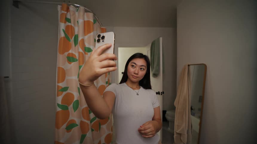 Young woman takes selfies on the bathroom at home