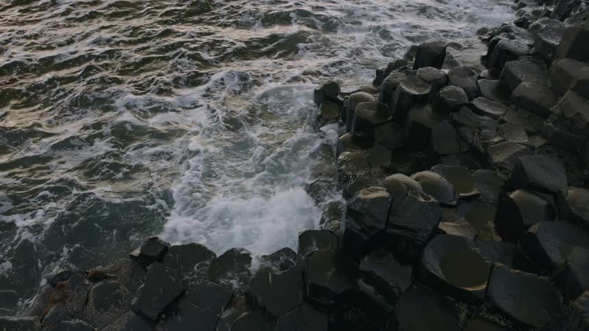 The waves from the sea crash onto the rocky shoreline