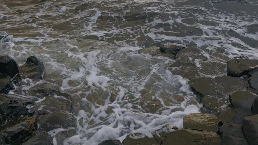 Small waves gently crashing over the rocks on the coast