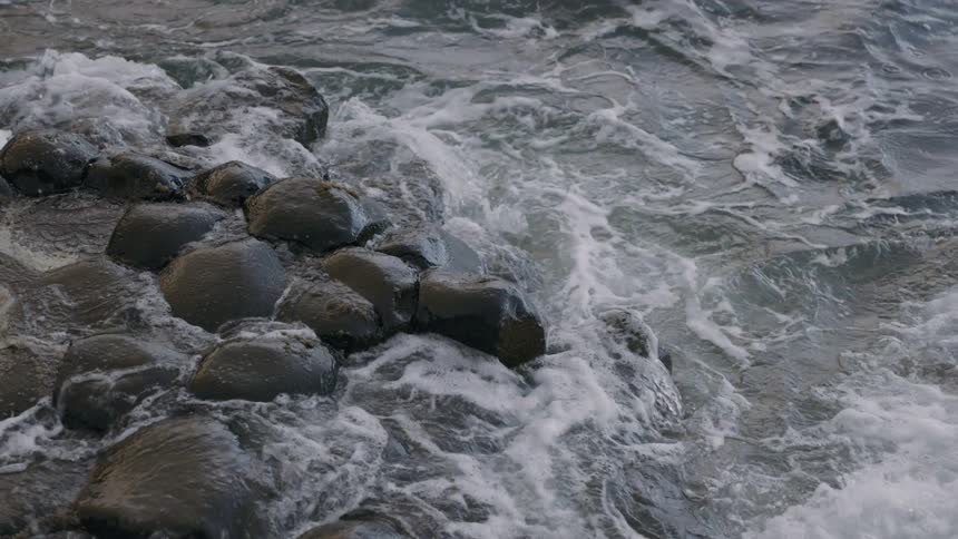 Ocean waves crashing towards the rock at the beach