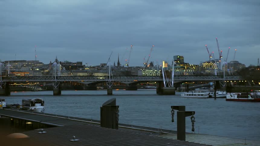 Boats are docked near a bridge by the city