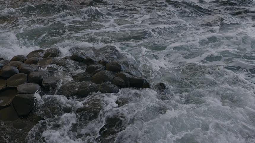 Slow motion of water waves splash against rocks along the coast