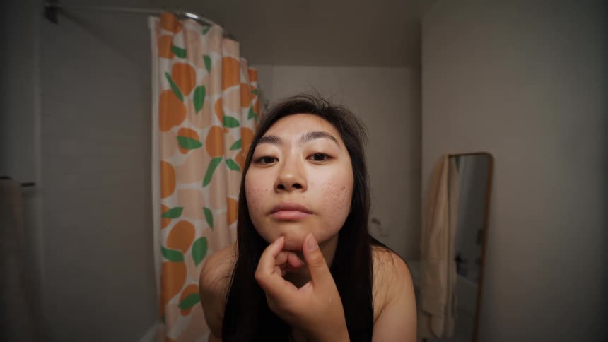 Woman brushes her hair in front of a mirror in the bathroom