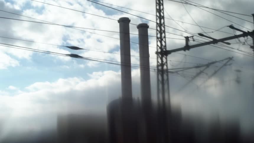 There are two tall chimneys behind power lines