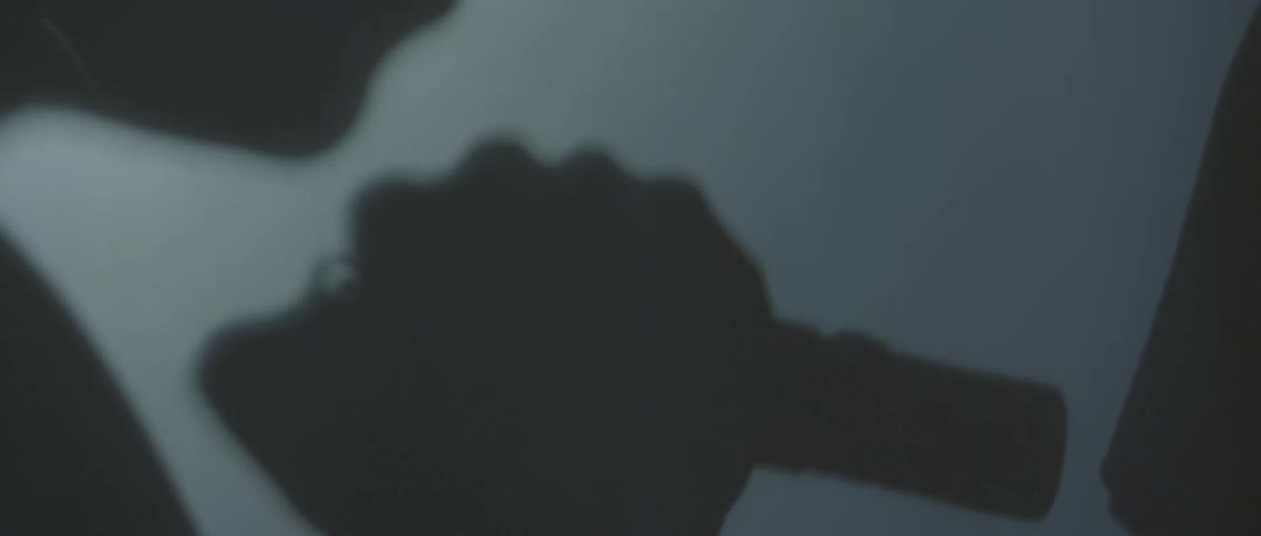 The silhouette of a man speaking before he clicks an object in his hand and the screen goes black