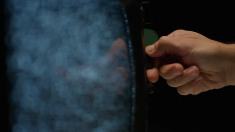White male hand turning a button on a vintage television set