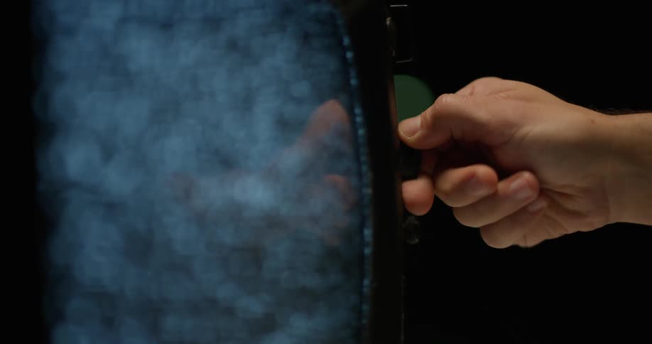 White male hand turning a button on a vintage television set