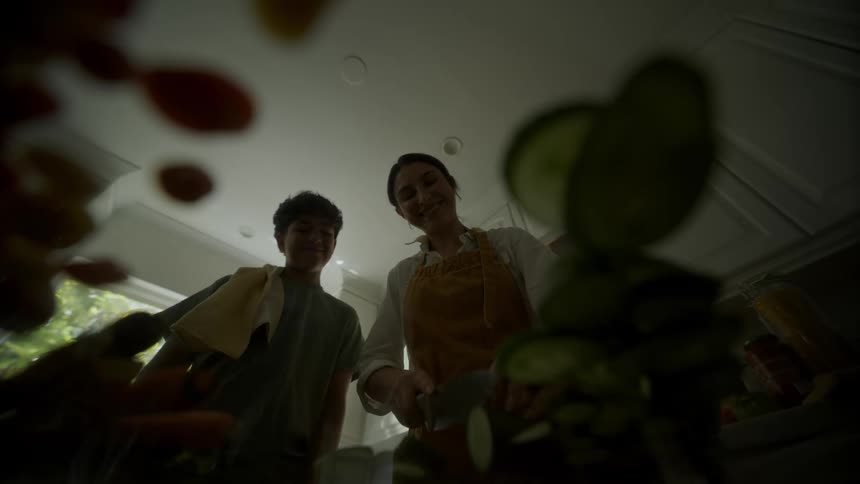 Mother slices vegetables turning to smile at son