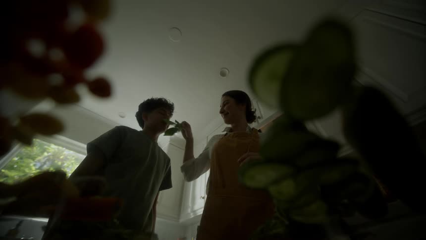 A woman caressing her sons face while they are in the kitchen