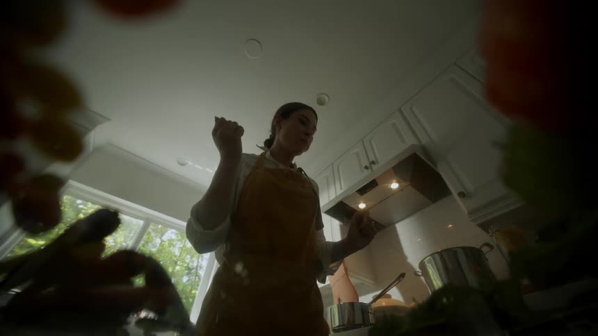 A point of view from the counter as a woman eats food and prepares food in her kitchen