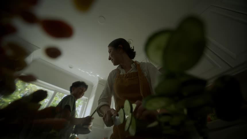 Mother smiles at son while she cuts vegetables