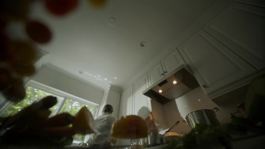 Point of view from a counter top of a woman cooking and preparing food in her kitchen using her hands to keep her in check