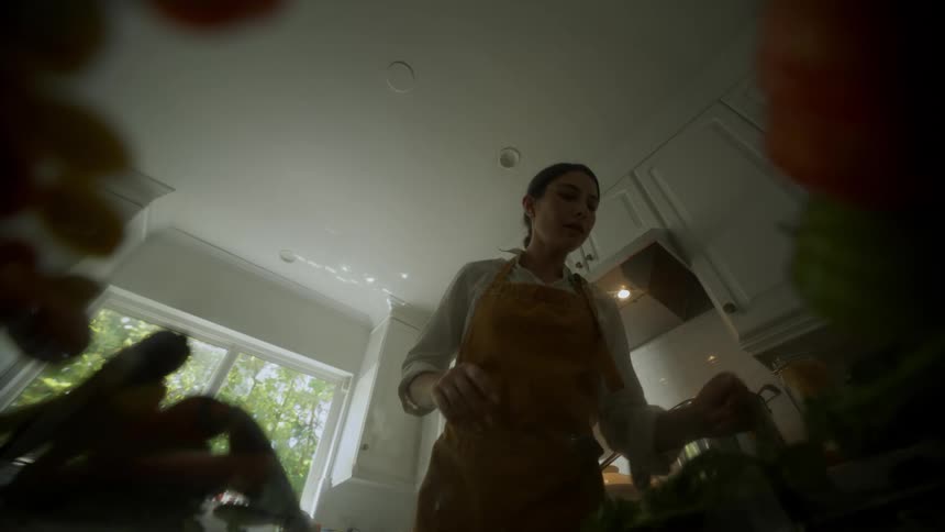 Point of view from a counter top of a woman preparing food and eating in her kitchen