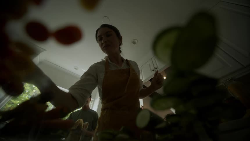 Woman and a teenager happily cooking vegetables