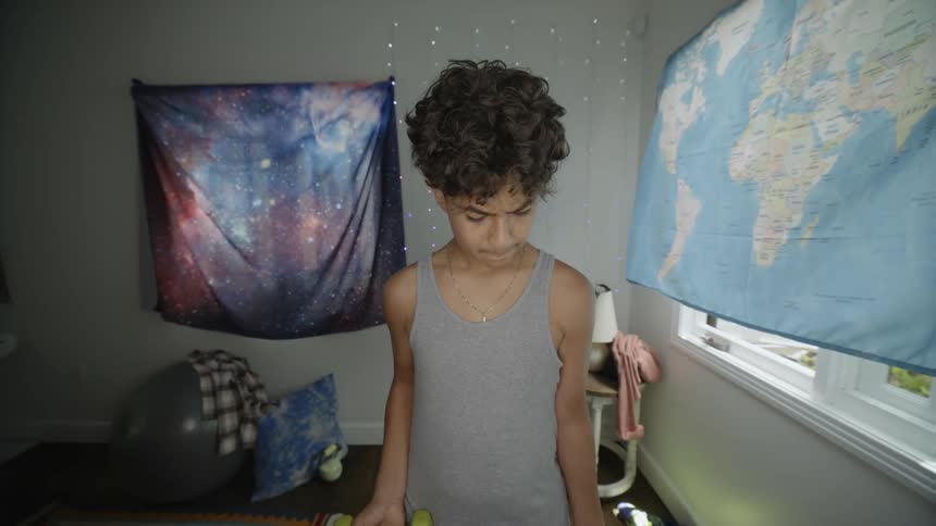 A teenager is lifting weights at home