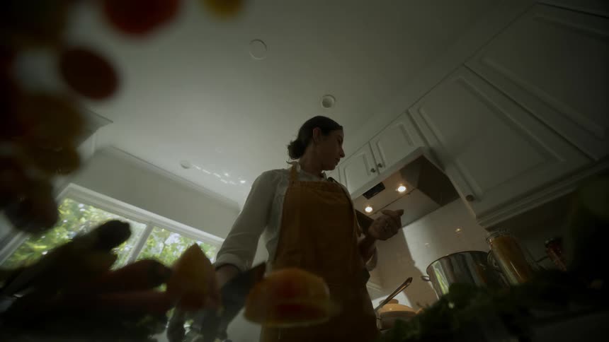 A point of view from a counter top of a woman cooking and preparing food in her kitchen