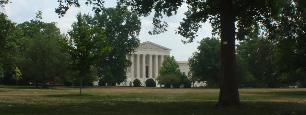 A classic construction with huge pillars in an environment full of trees that are moving with the wind