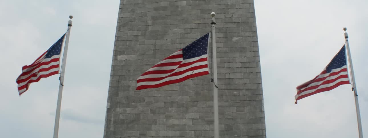 The flags are flying in the wind in front of the monument