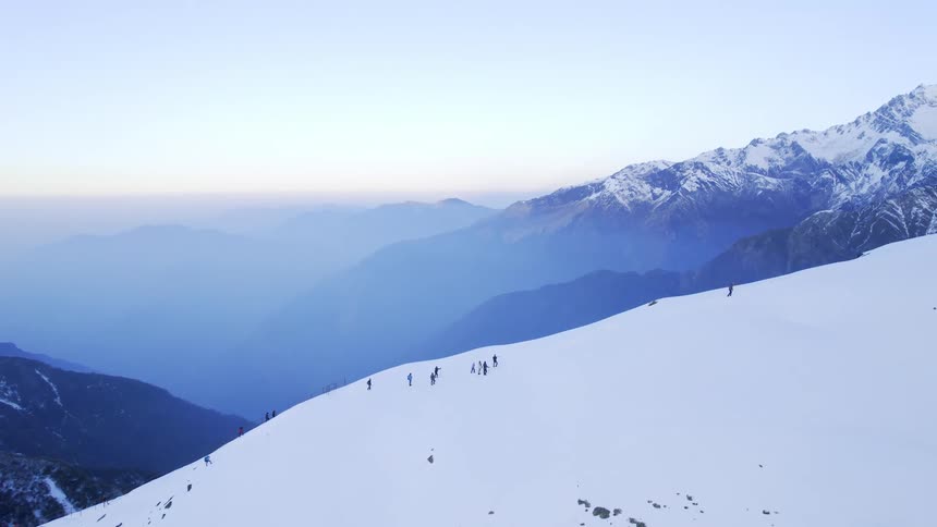 Aerial view of a group of people hiking on snowy mountain slope