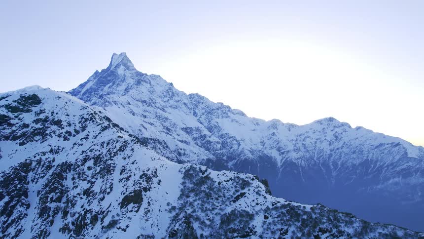 A large snowy mountain range with a valley in the center during the day
