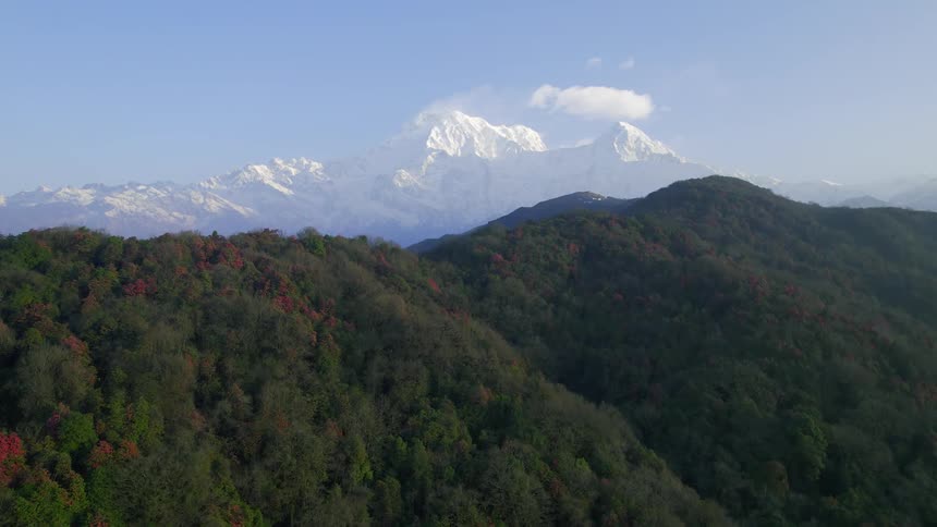 Foggy valley separates forest covered mountains from snow covered mountains