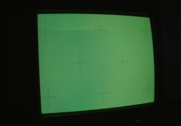Close up of a green screen on a television monitor in a black dark room