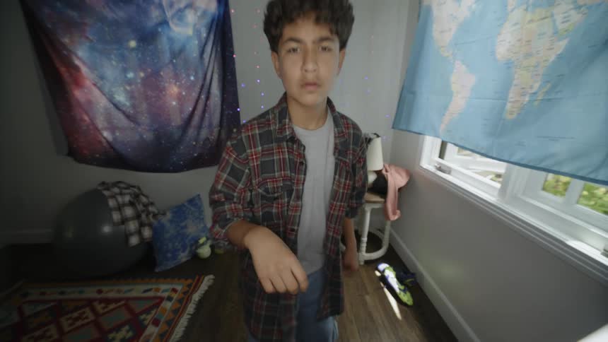 A boy pointing at the camera and then doing dance moves