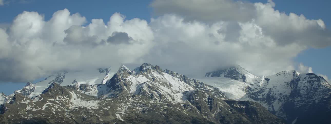 A view of a group of cold mountains and a big cloud in the background