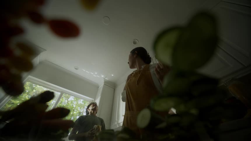 Woman with apron and shirt eats food with boy in the kitchen