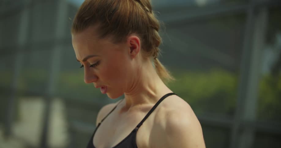 A white woman putting on a sport bra while relieving herself to prepare for an exercise activity