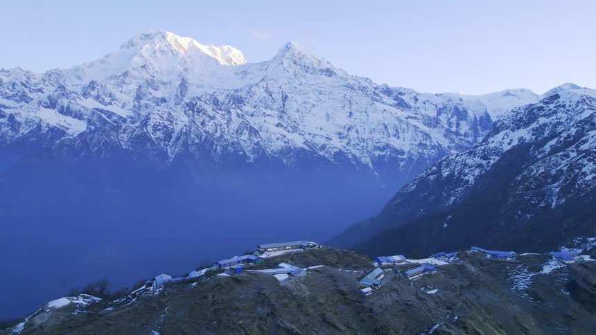 A large snowy mountain range with a base campsite near a large valley