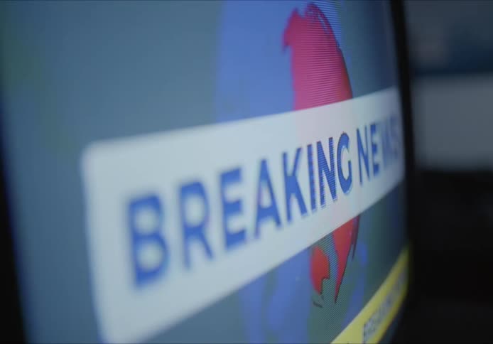 A close up of a television screen with news information casting across the screen