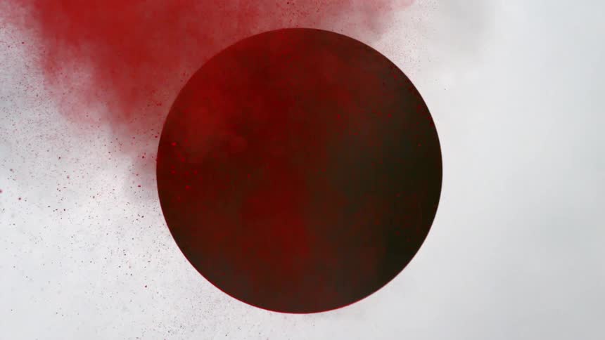 Red powder shooting out of a circular hole in wall