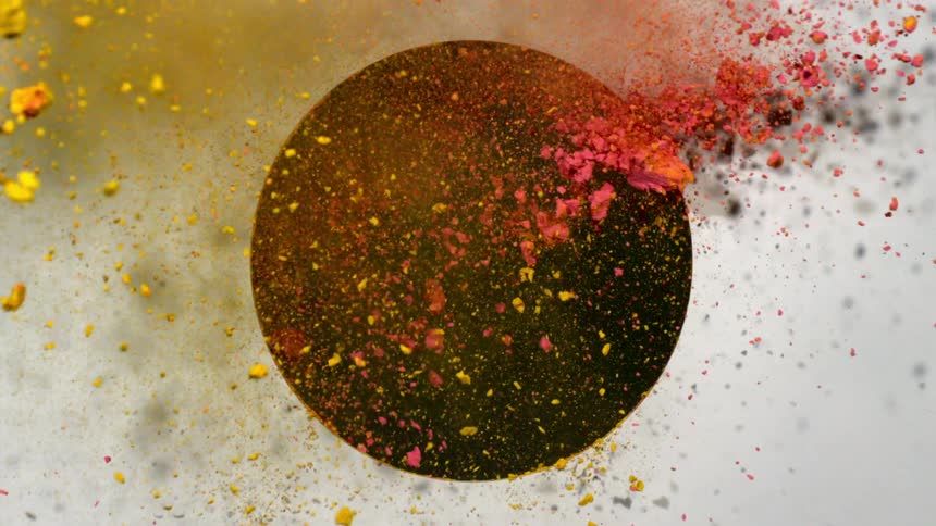 Yellow and red powder shooting out of a round hole in wall