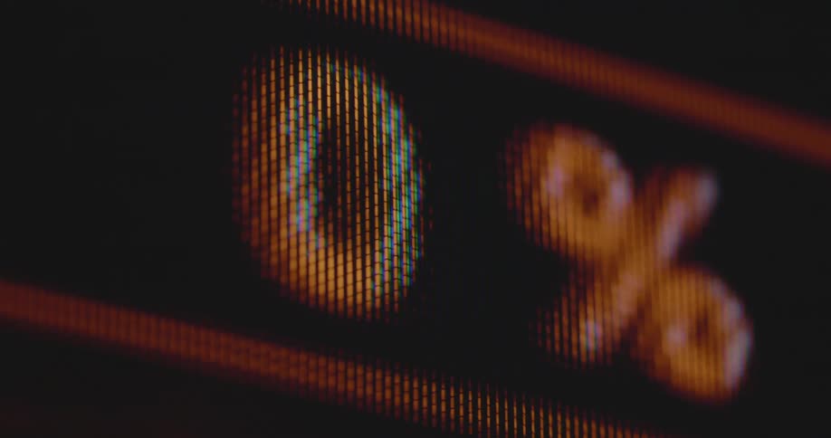 A closeup of a retro computer screen shows a battery indicator or loading bar with charging level in percentage increasing and decreasing and turning red after displaying fully charged indication with 100% in green