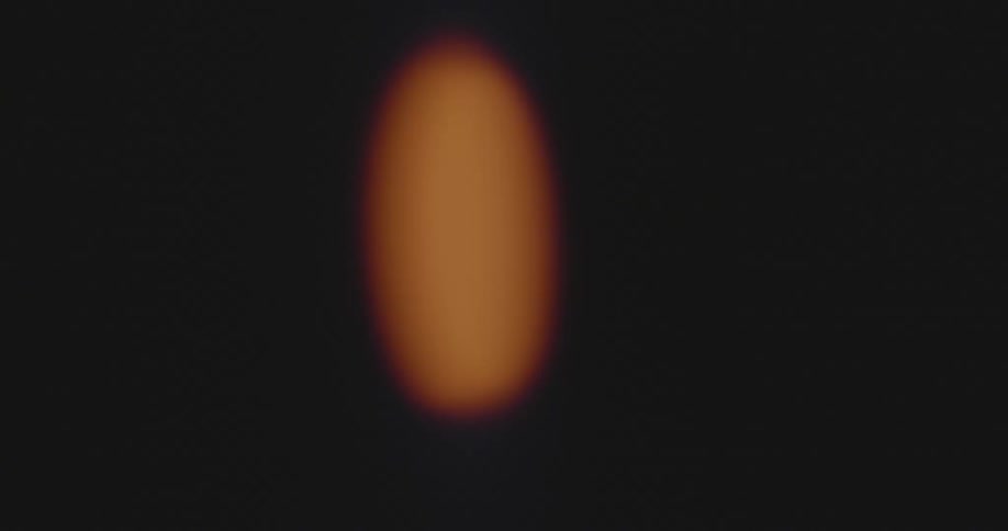 The neon lights of an illuminated orange button flashes and spins on an old tube television as warning or alert signal with distortion and glitches