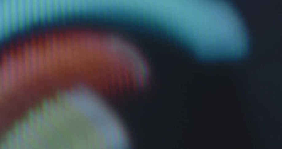 Extreme macro closeup shows bent and curved lines of colorful circle rainbow animation graphics displayed on a vintage tube TV screen with visible rgb pixels during dynamic rotation and spin
