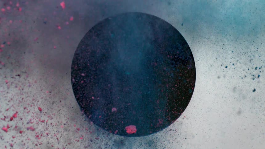 Red and blue dirt fly out of a black circle